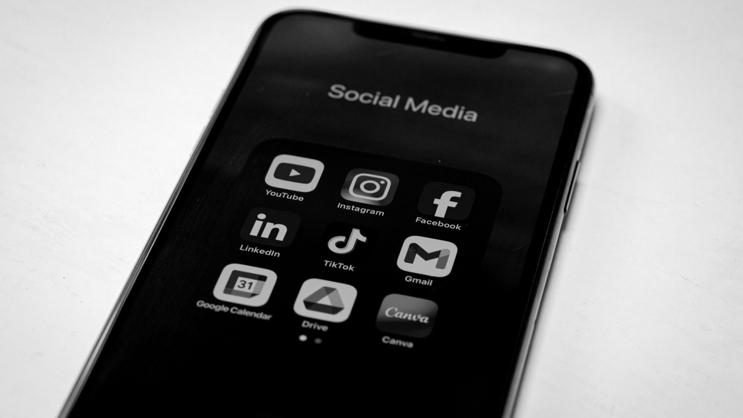 SNS アプリのアイコンが並ぶスマートフォンをモノトーンで写したイメージ写真（SocialDog の画面ではありません）